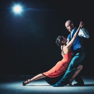 Elegant couple performing tango under a dramatic spotlight, showcasing passion and grace.